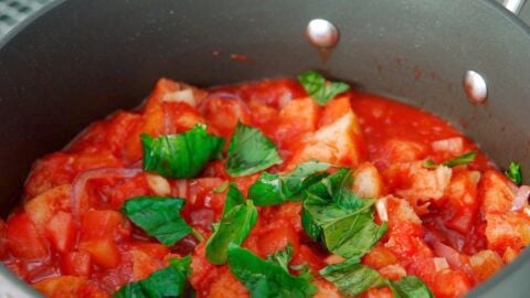 Adding fresh basil leaves to bread and tomato soup.