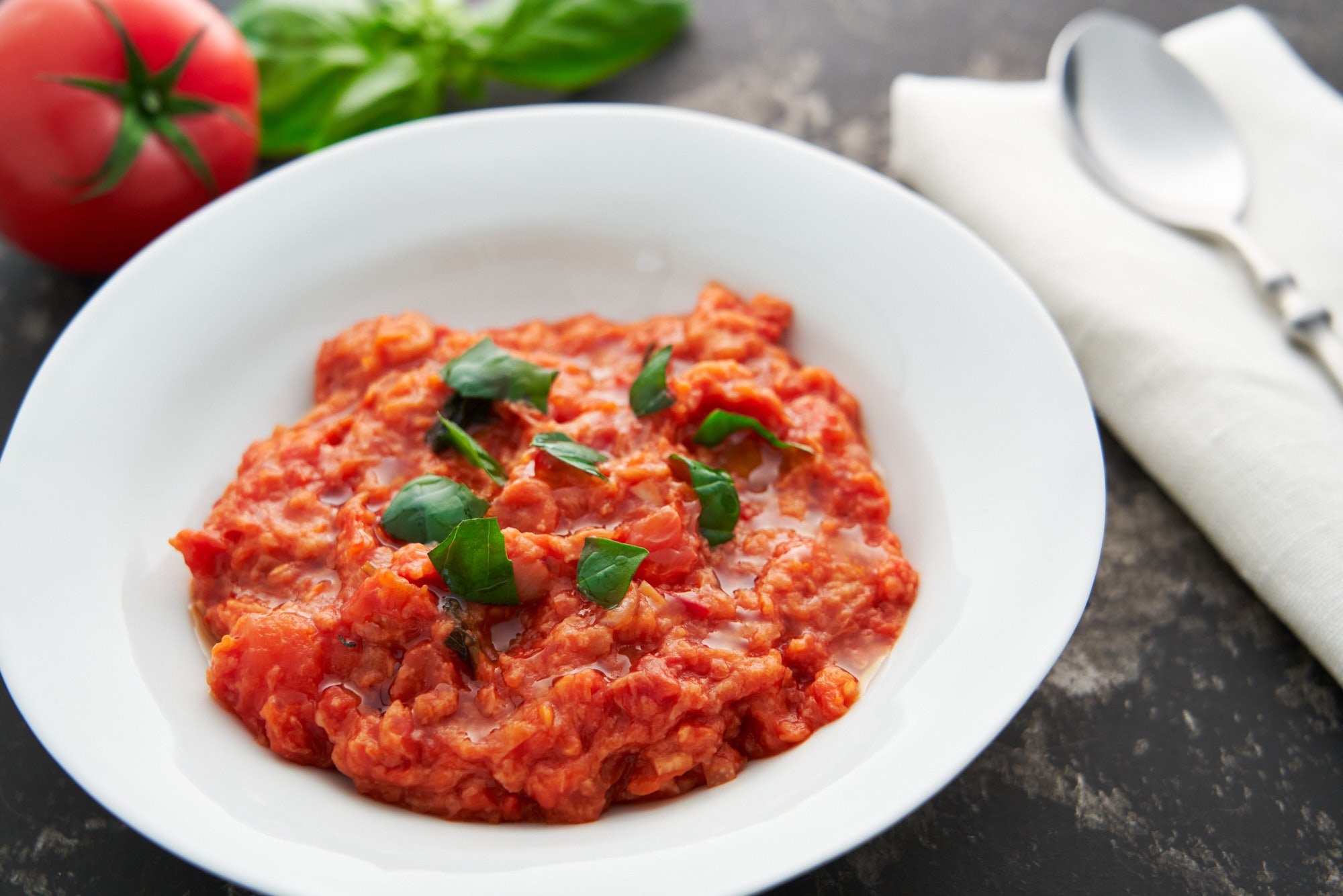 Pappa al Pomodoro, or Tuscan Bread and Tomato Porridge made with a flavorful tomato soup thickened with crusty bread, served with fresh torn basil and a drizzle of olive oil.