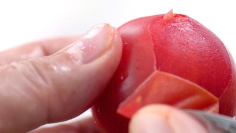 Peeling tomato with a paring knife.