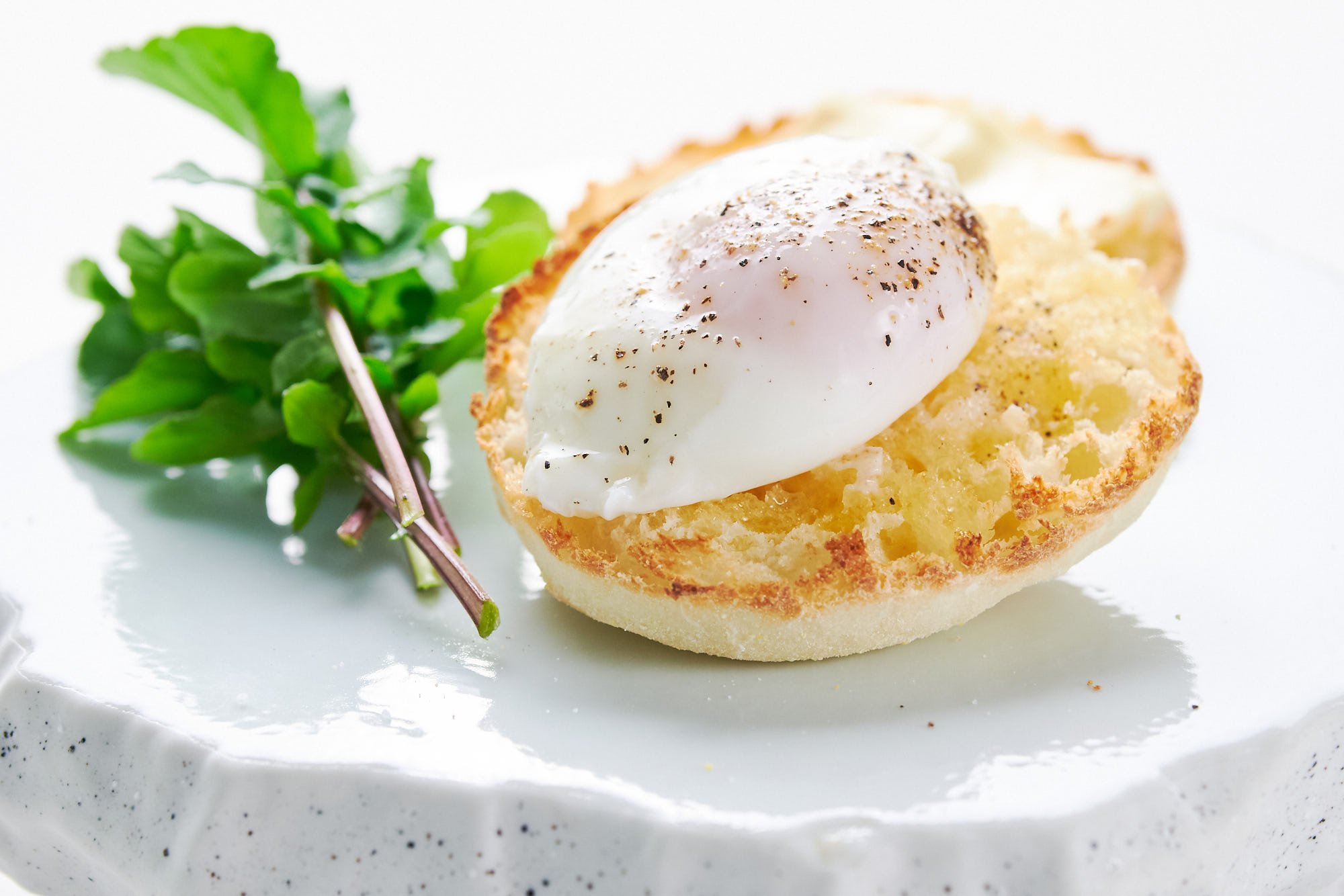 Perfect oval poached egg without whispy egg whites on toasted english muffin with arugula.