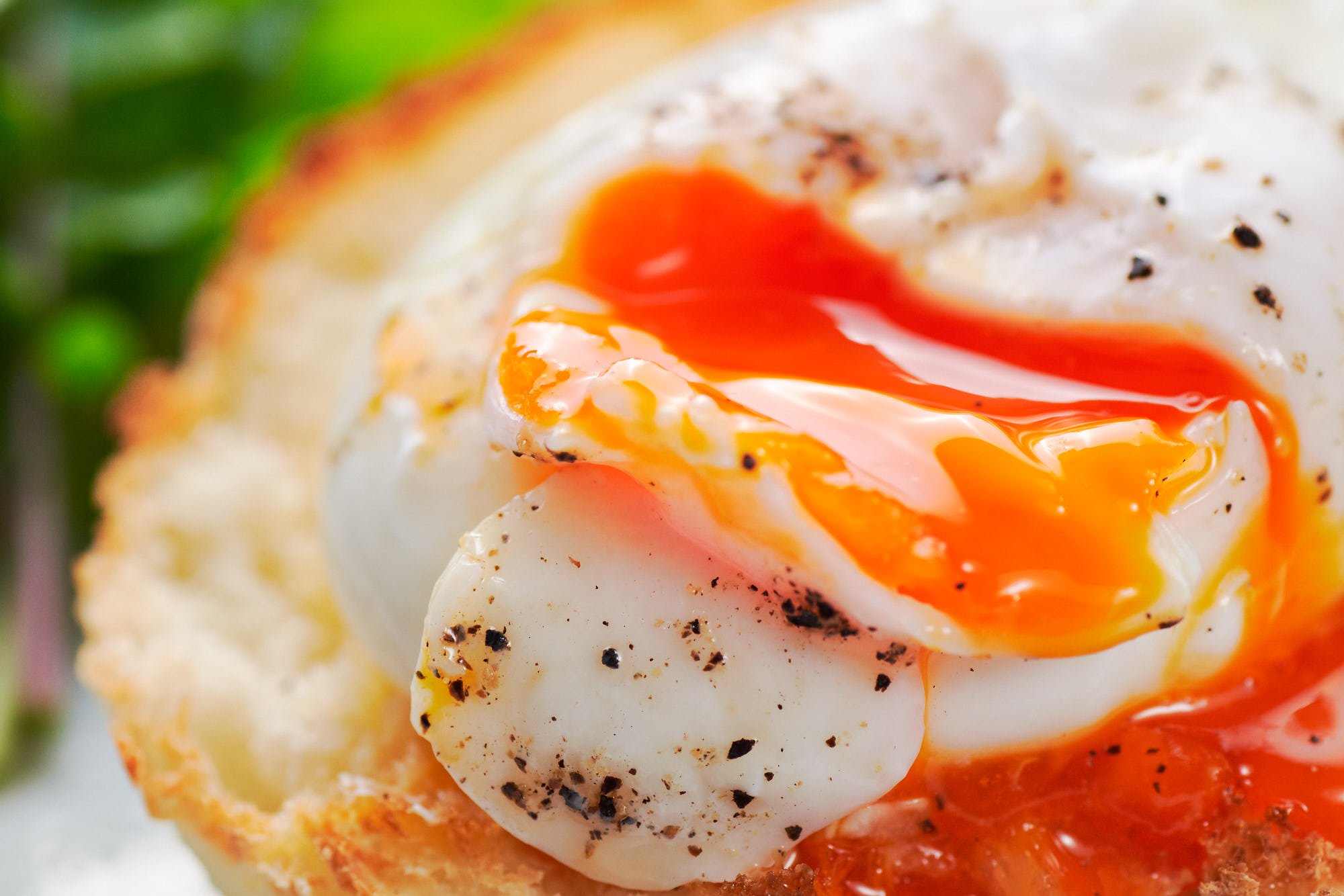 Golden egg yolk pouring out of a perfectly poached egg.