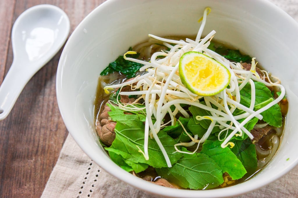 A plate of condiments such as basil, cilantro, bean sprouts and lime allow you to customize your own bowl of pho. 