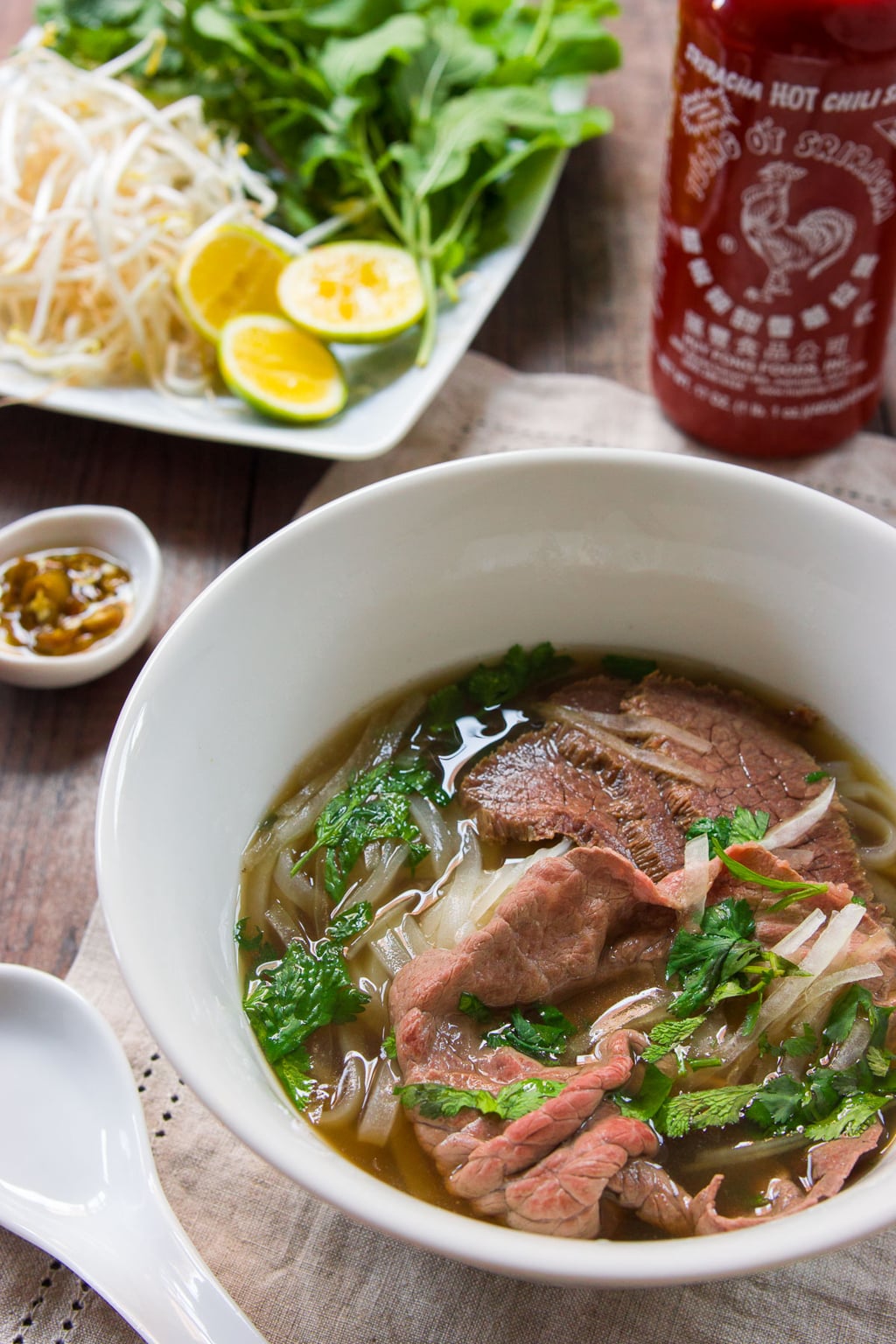 Pho, a Vietnamese rice noodle soup with spiced beef broth and slices of rare steak and condiments such as basil, bean sprouts and lime.