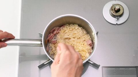 Boiling instant ramen noodles with bacon.