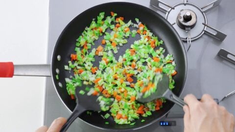 Stir-frying cabbage, onions and carrots in a large frying pan.