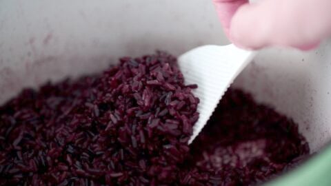 Fluffing cooked Riceberry using a rice paddle.