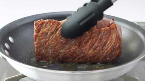 Browned wagyu beef sizzling in a pan.