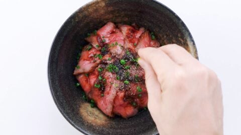 Roast beef rice bowl garnished with black pepper and scallions.