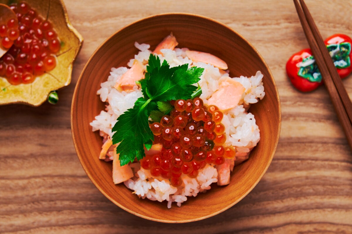 A bowl of salmon rice (salmon takikomi gohan) topped with ikura and mitsuba.