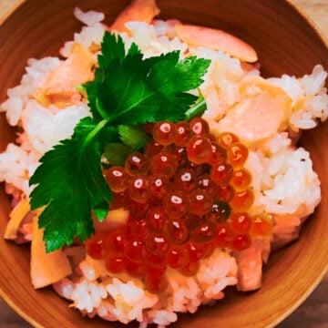 A bowl of salmon rice (salmon takikomi gohan) topped with ikura and mitsuba.