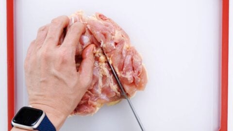 Cutting chicken thigh into strips.