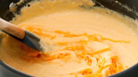 Melting cheese into a pot of grits.