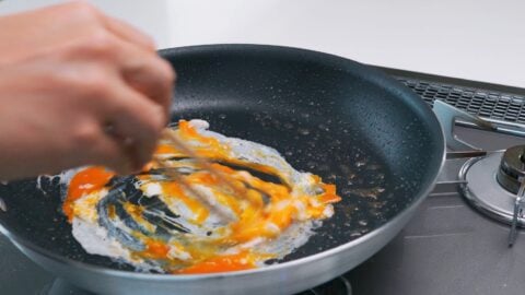 Scrambling egg in a frying pan.