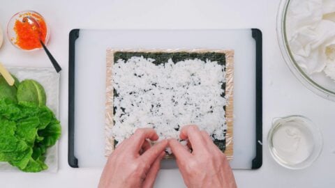 Spreading sushi rice on a sheet of nori.