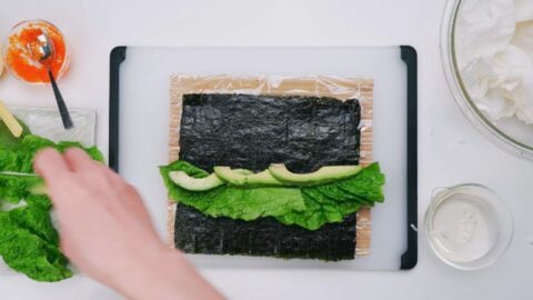 Lettuce and avocado on nori to make a sushi roll.