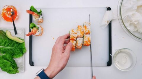 Slicing shrimp tempura sushi roll.