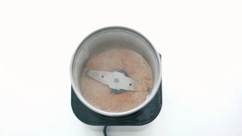 Grinding dried scallops into a powder in a coffee grinder for chili oil.