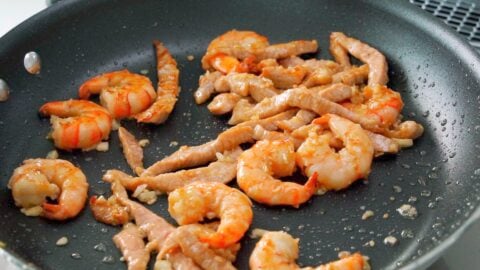 Marinated pork and shrimp being stir-fried for Singapore Noodles