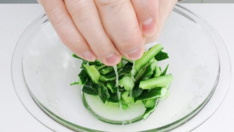 Squeezing excess water out of smashed cucumbers.