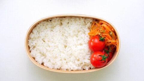 Rice, cherry tomatoes and carrot salad packed into a bento box.