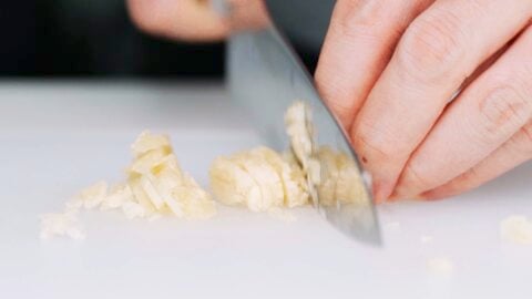 Chopping smashed garlic.