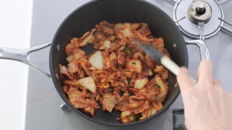 Stir-frying marinated pork belly and kimchi.