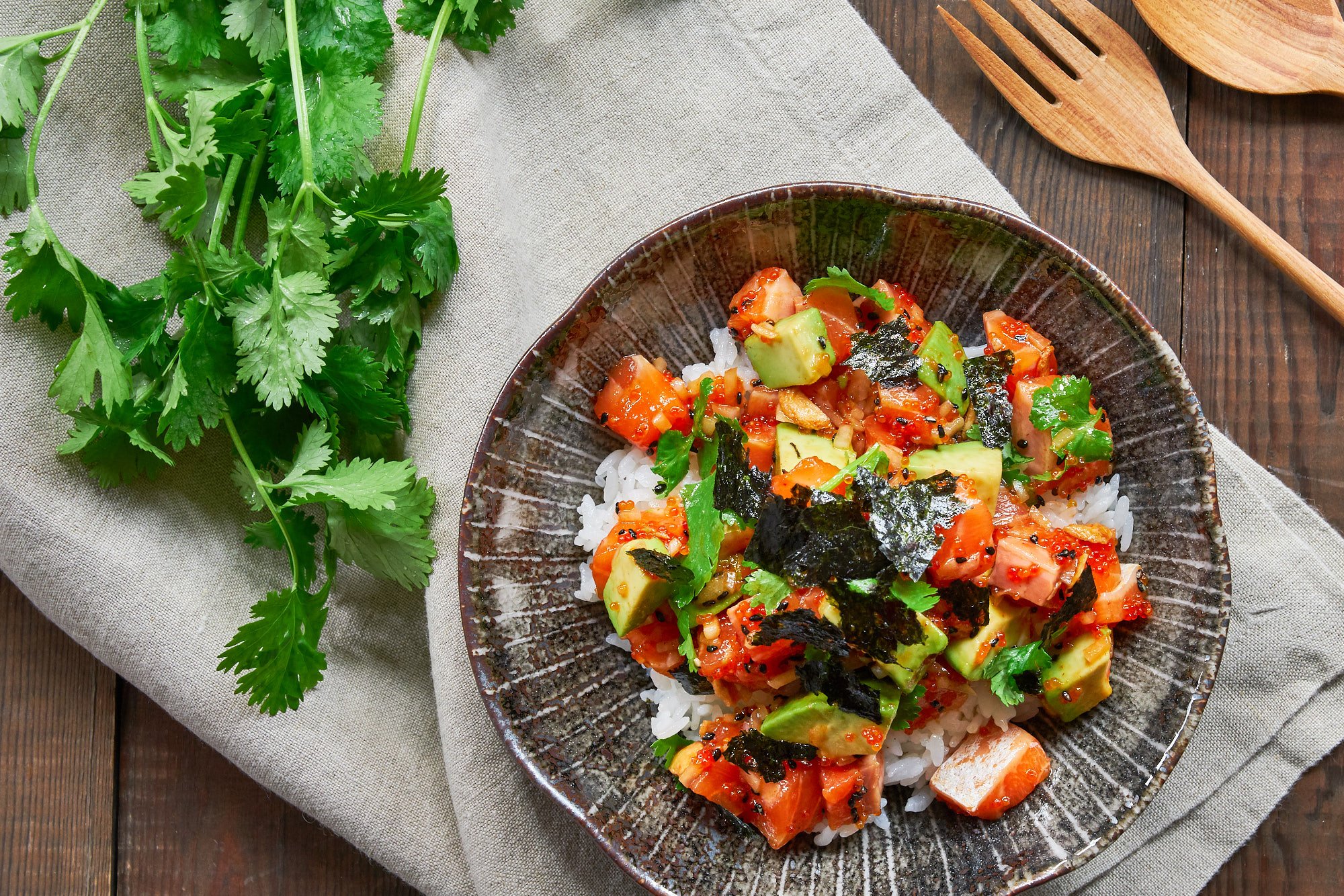 The best Spicy Salmon Poke recipe. Rich salmon and creamy avocado marinated with a sesame sriracha sauce and mixed with crunchy tobiko, crisp sweet onions and fresh cilantro served over a bowl of hot rice.