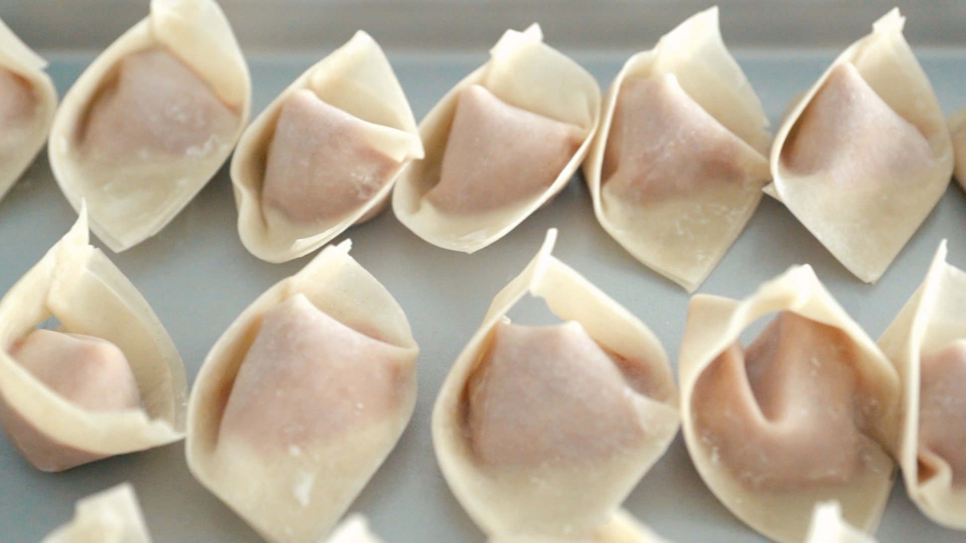 Wrapped wontons on a try look like people with their hands crossed.