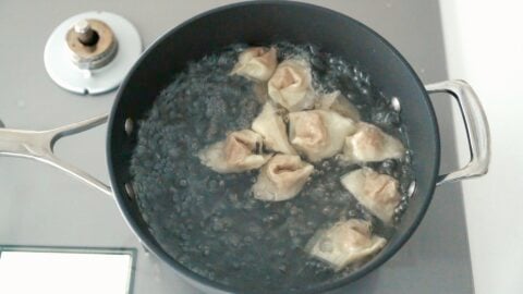 Boiling Chengdu-style wontons in chili oil.