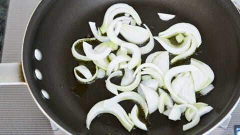 Spring onions in a frying pan with olive oil for making spring pasta.