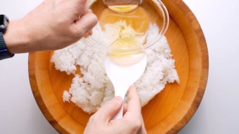 Sushi vinegar being poured over hot rice.