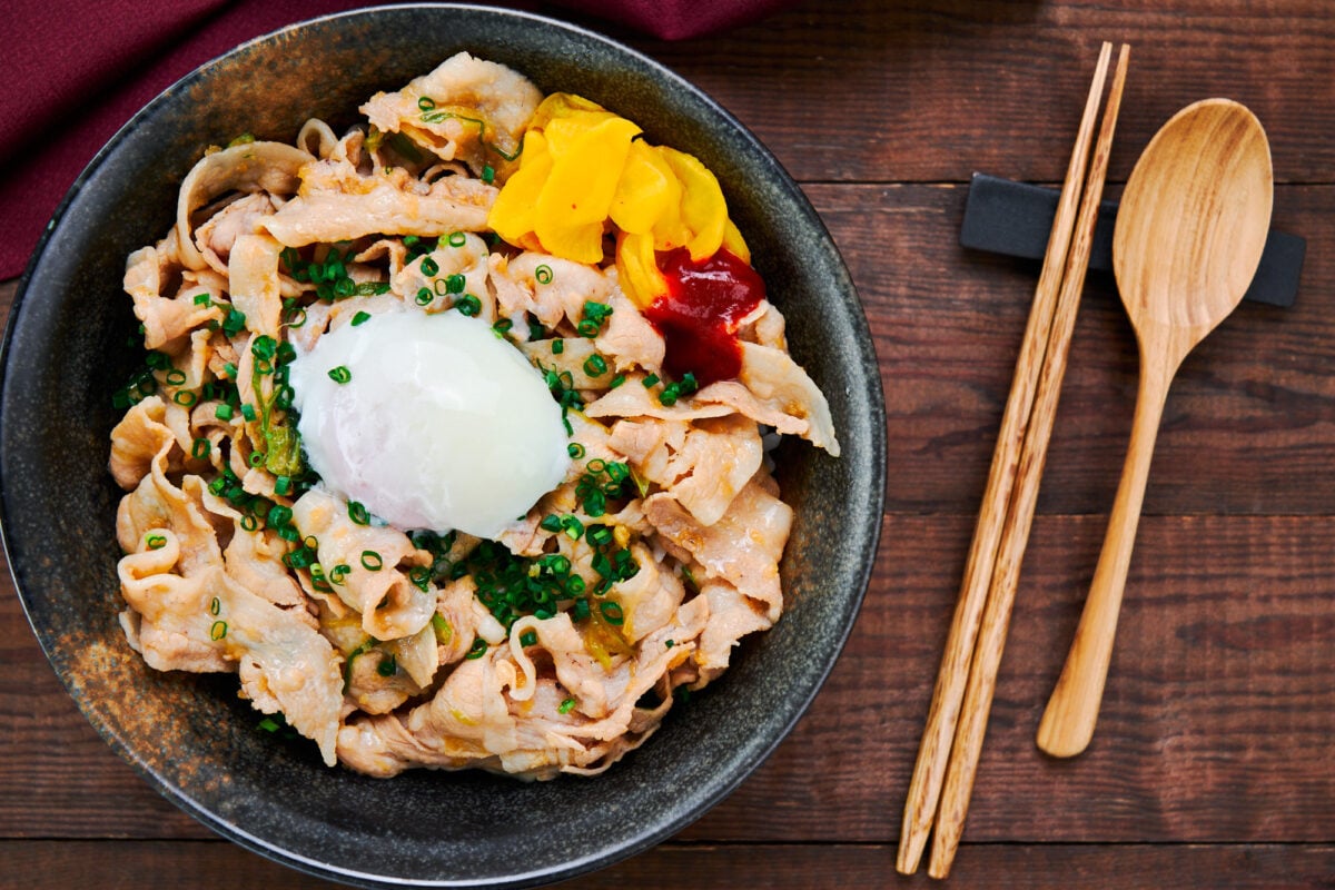 Pork and garlic rice bowl topped with a slow-cooked egg, pickles, and chili paste.