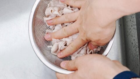 Draining poached pork for making Sutadon.