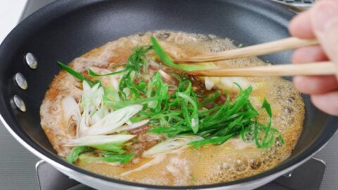 Simmering garlic sauce with sliced scallions.