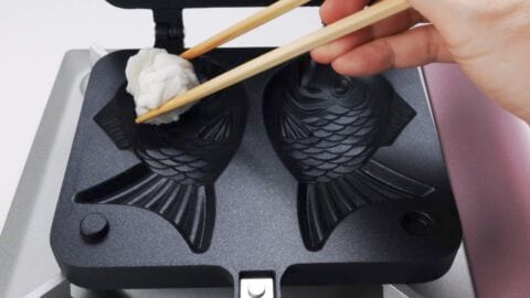 Greasing a Taiyaki mold with an oiled paper towel.