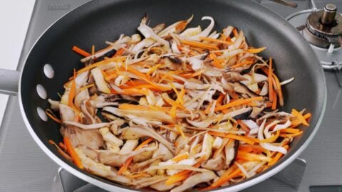 Sauteing a mixture of root vegetables and mushrooms for cooking with Takikomi Gohan.