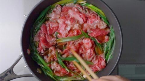 Beef and scallions simmering in dashi stock to make Tanindon.