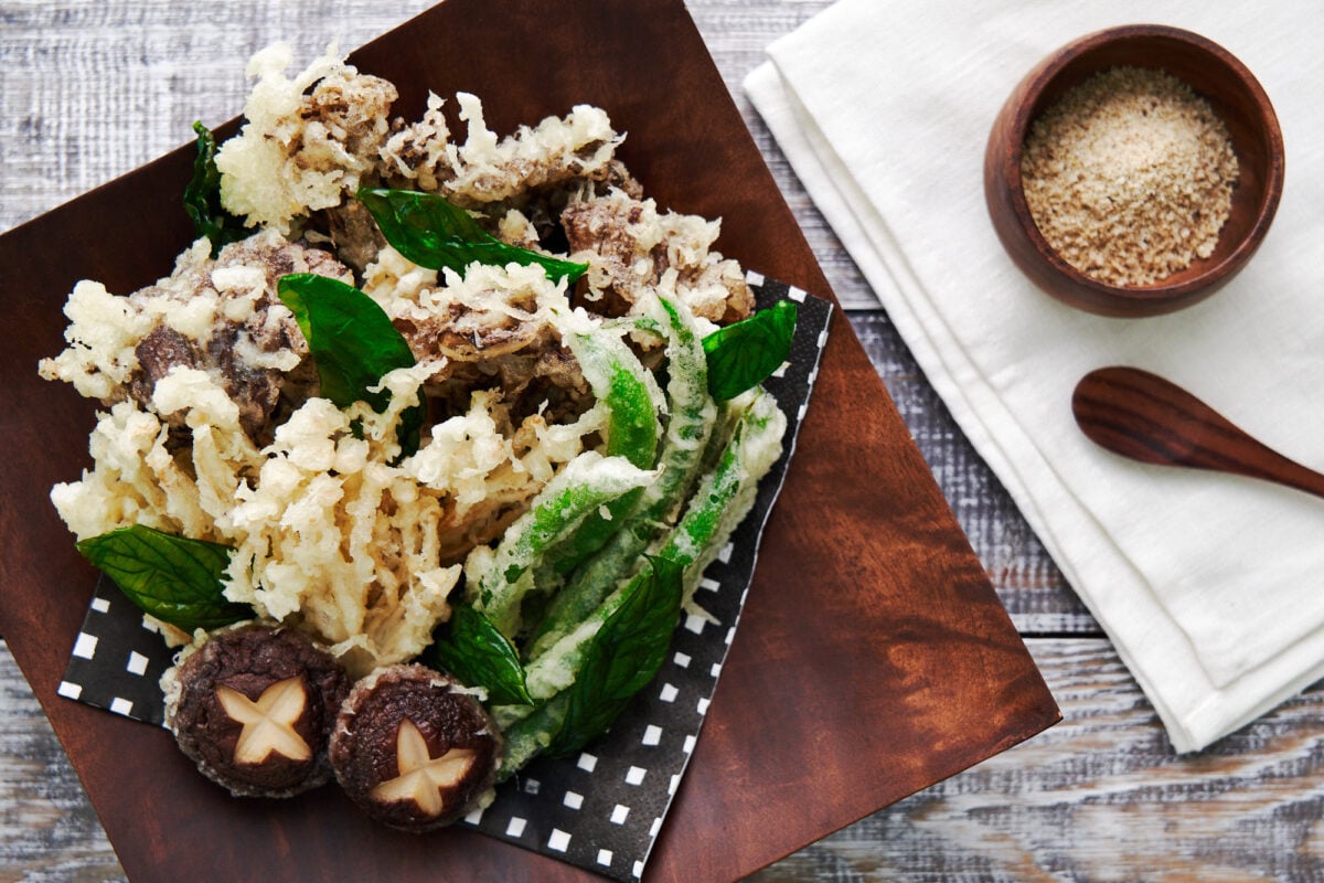 Ultra-crispy mushroom tempura on a wooden plate with truffle salt.