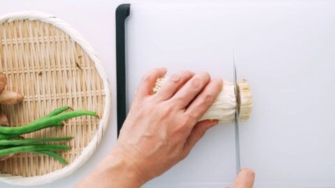 Trimming growing medium off of enoki mushrooms.