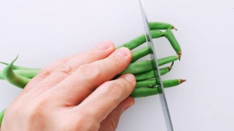 Trimming the tops off of green beans for tempura.