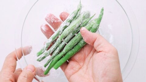 Coating green beans with starch to make the tempura batter stick.