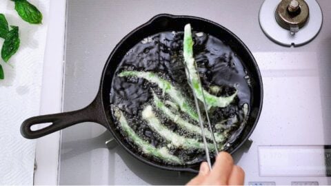 Frying tempura green beans in a cast iron pan.