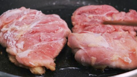 Frying chicken teriyaki, skin-side down.