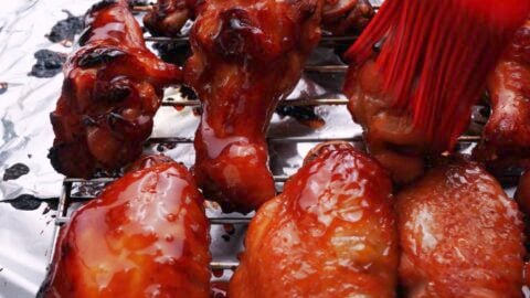 Glazing chicken wings with glossy teriyaki sauce.