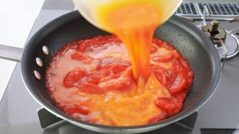 Adding eggs to stir-fried tomatoes.