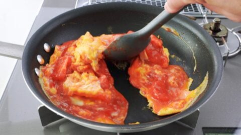 Mixing stir-fried tomatoes with eggs.