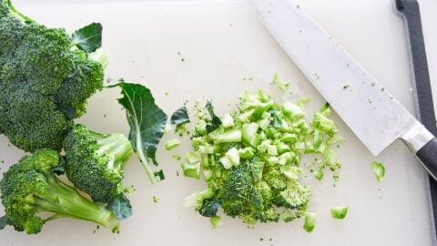 Broccoli chopped finely on a cutting board, for making creamy broccoli and cheese soup.