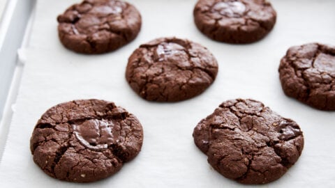 Vegan chocolate cookies straight out of the oven with melted chocolate oozing out.