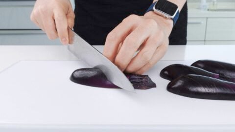 Scoring eggplant skin with knife.