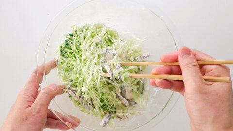 Mixing shredded cabbage, mushrooms and scallions together with flour.